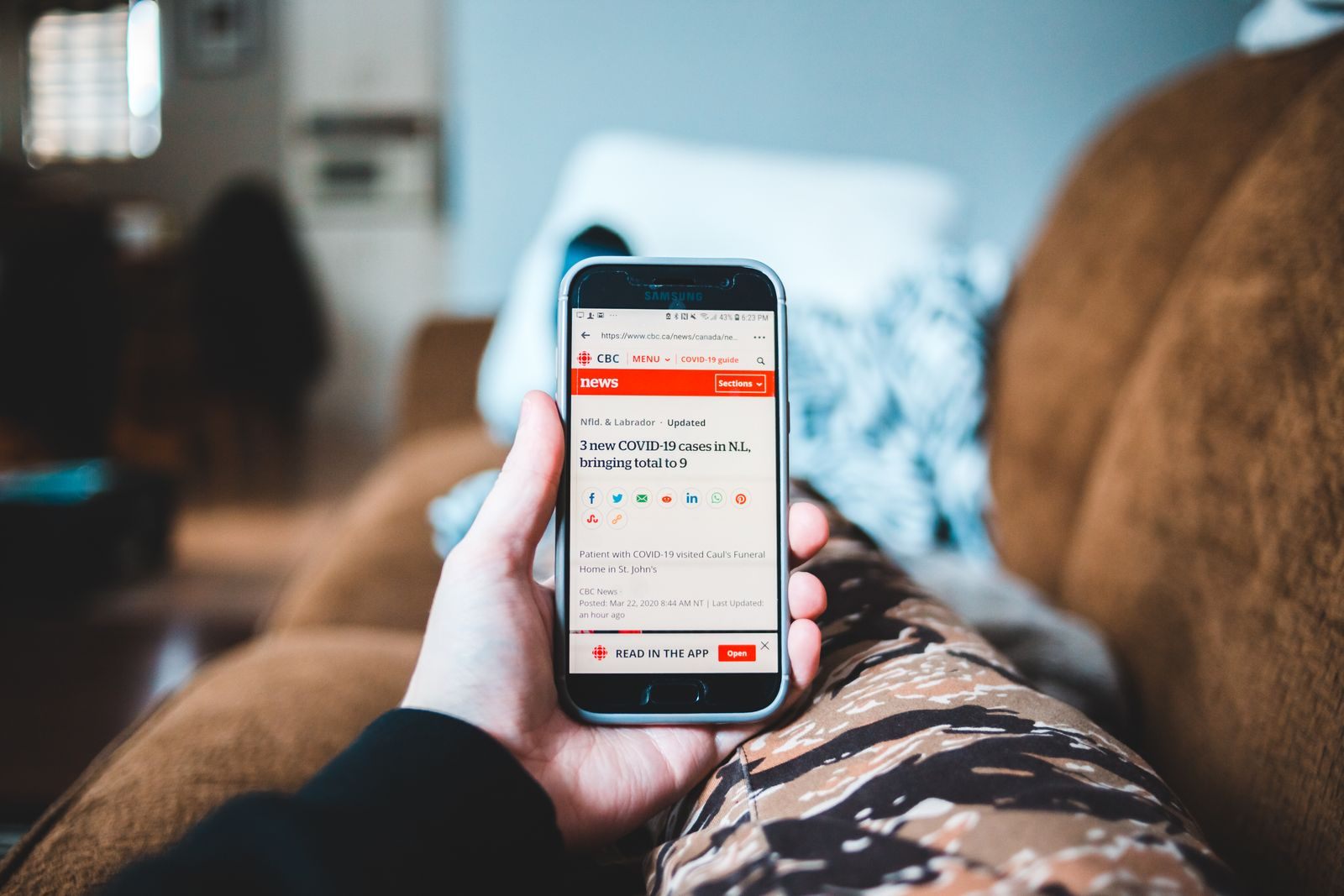 Person reading cruise news today on a smartphone while relaxing on a sofa
