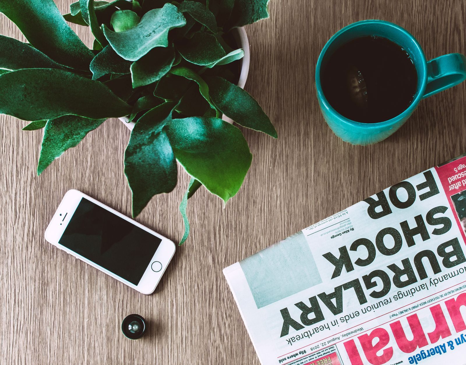 Tabloid newspaper with a shock headline beside a phone and coffee mug